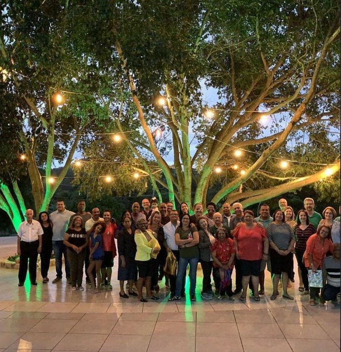 Grupo reunido sob árvores iluminadas à noite